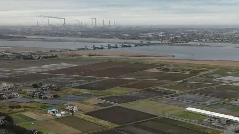 上空から見た田畑と利根川。川の向こうに工場の煙突が並ぶ